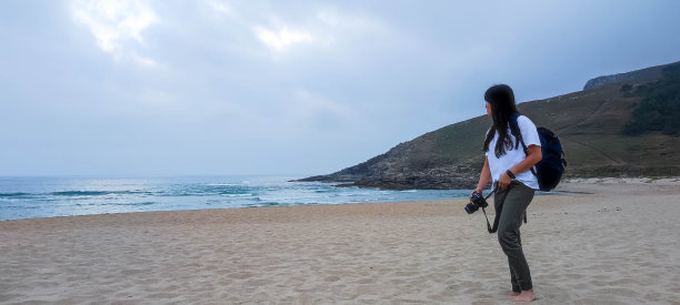 女孩在海滩上拍照图片下载