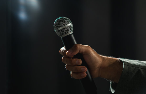 在公司商业活动中，自信成功的演说家在舞台上讲话，聚光灯照亮了黑暗。在会议大厅演讲的公众演说家。喜剧演员。图片下载