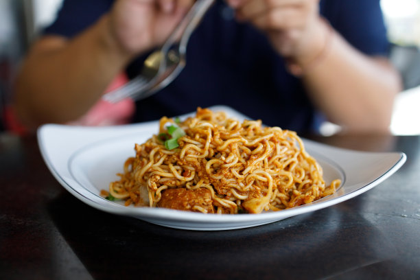 一名亚洲男子在当地小贩的摊位上吃Mee Goreng的图片图片下载
