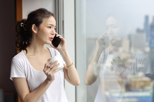 肖像自信和美丽的年轻亚洲女商人站在咖啡杯和看向远处的现代酒店与城市模糊的背景。成功的商业和生活理念图片下载