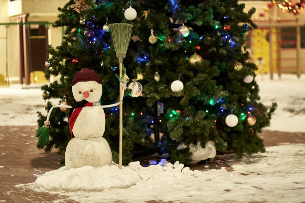 一个快乐的雪人在冬天的仙境有树和花环。在多层建筑的院子里准备圣诞节的概念。有空间复制。高质量照片图片下载