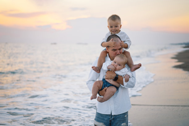 祝您父亲节快乐。父亲和孩子们在海滩上玩耍。图片下载