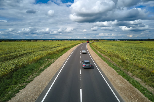 绿色农田之间的城际公路鸟瞰图，高速行驶的汽车。无人机对高速公路交通的俯视图图片下载