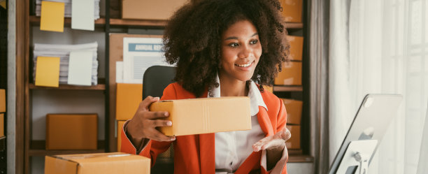 非裔美国女商人在仓库工作，准备中小企业的包裹箱，以便在小型企业的家庭办公室运送。图片下载