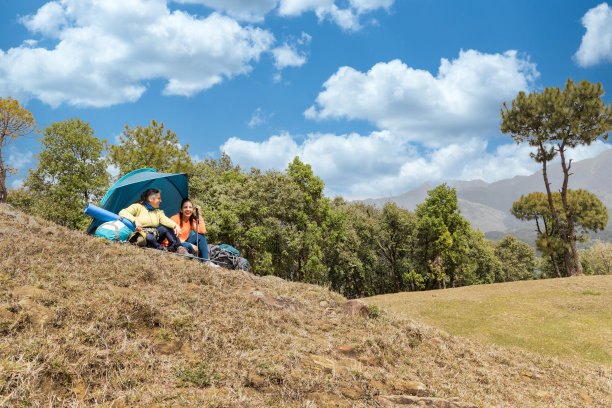 两个女人坐在山间绿草地上的帐篷里。图片下载