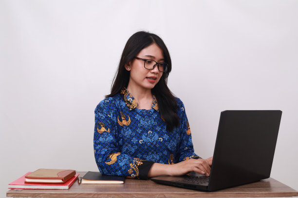 身穿印尼传统工人制服的亚洲女性正摆弄着笔记本电脑图片下载