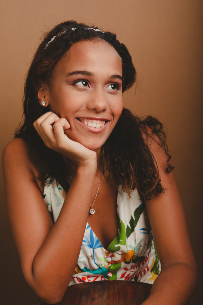 一个漂亮的十几岁的女孩倚在木凳上，双手放在下巴上。图片下载