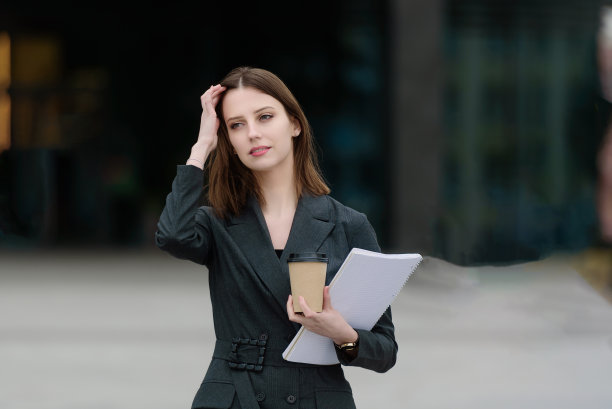 一个穿西装的女人带着文件和咖啡去参加商务会议。图片下载