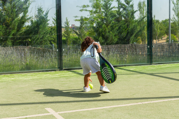 小女孩在球拍场上从地上捡起一个网球图片下载