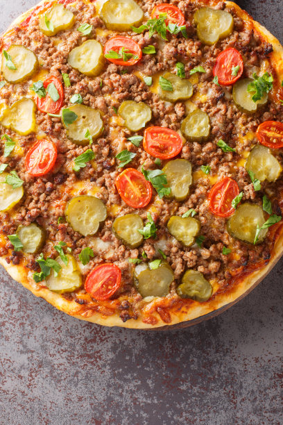 美味的热汉堡披萨，有碎牛肉、西红柿、泡菜和奶酪，放在桌子上的木板上。垂直俯视图图片下载
