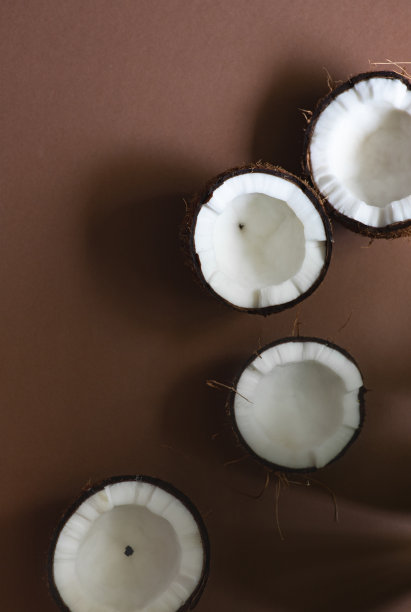 极简主义的夏季构图与成熟的椰子在棕色工艺背景与热带树叶的阴影。前视图。本空间图片下载