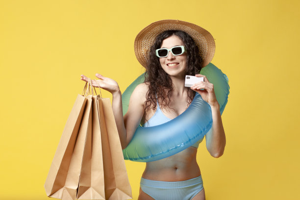 穿着蓝色泳衣的年轻女孩拿着充气游泳环，手里拿着购物包和银行卡图片下载