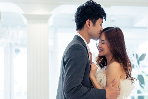 亚洲迷人的未婚夫夫妇在婚礼工作室亲吻对方。美丽的年轻男女在新娘店的试衣间享受着准备婚礼的快乐和放松。图片下载