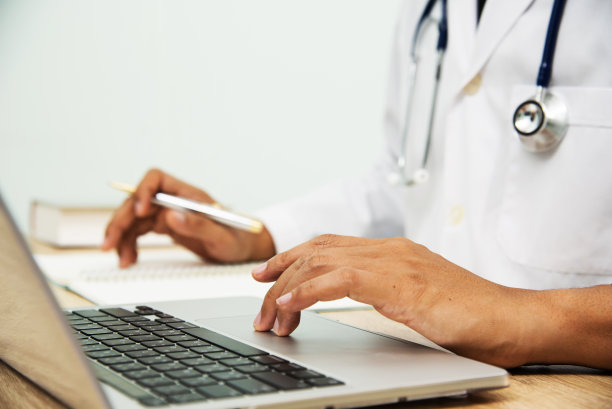 穿着医疗制服的医生在医院的办公桌上用电脑笔记本工作图片下载