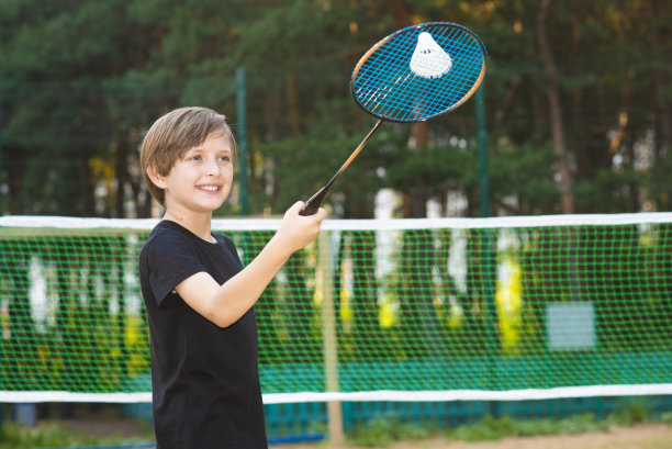 微笑的小运动员打羽毛球。快乐的孩子手里拿着球拍图片下载