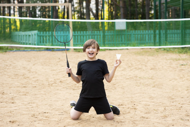 微笑的小运动员打羽毛球。快乐的孩子手里拿着球拍图片下载