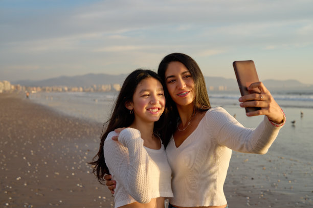 拉丁裔母亲和女儿在拉塞雷纳海滩上开心地自拍图片下载