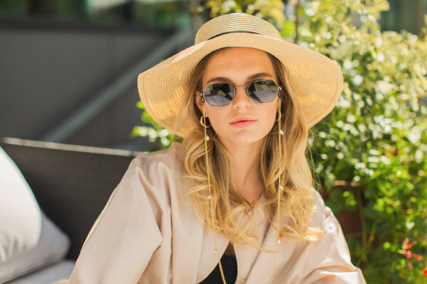 戴着墨镜，穿着浅灰色西装的金发女商人。女商人。夏天的时尚。戴帽子的模特图片下载
