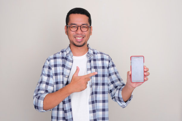 一个男人开心地笑着，指着他手里空白的手机屏幕图片下载