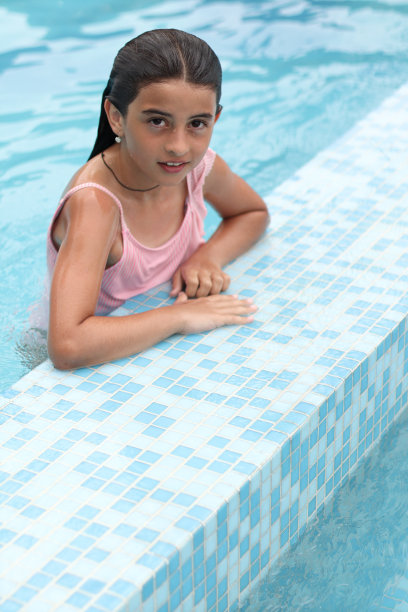 一个漂亮的年轻女孩在游泳池里。图片下载