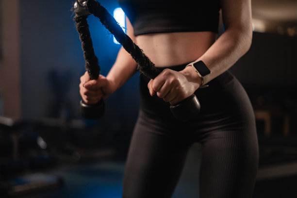 近距离拍摄女性在健身房使用绳索进行手臂锻炼肌肉三头肌训练的双手。运动、健身、生活方式、以人为本。黑暗的照片。图片下载