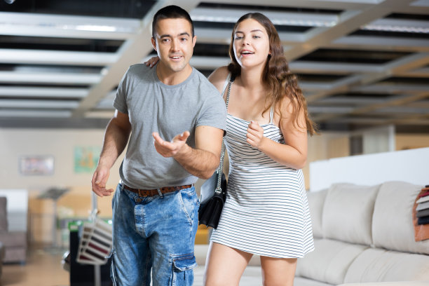 夫妇俩站在家具店里，中间摆放着各式各样的沙发图片下载