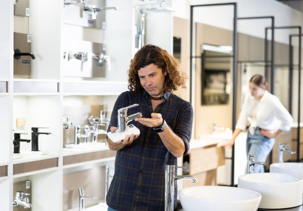 一个自信的男人在店里挑选新的浴室水龙头图片下载