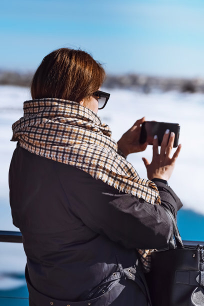 快乐的女人用手机微笑着走在冬天图片下载