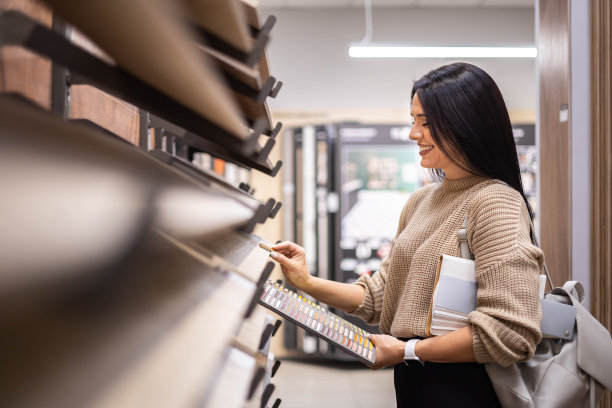 快乐的黑发女室内设计师在商店挑选地砖颜色纹理样品图片下载