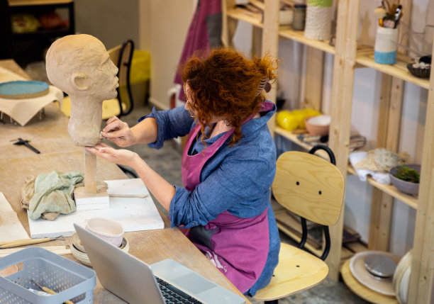 在陶艺工作室车间雕刻人头的女雕刻家。图片下载