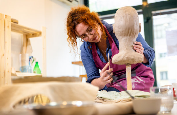 在陶艺工作室车间雕刻人头的女雕刻家。图片下载