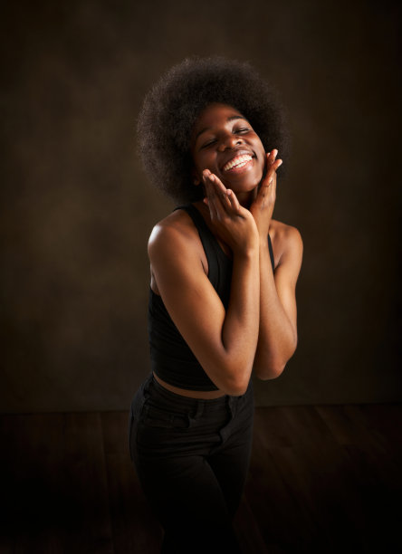 一个年轻的黑人妇女用手抚摸着她的脸，露出她完美的微笑图片下载