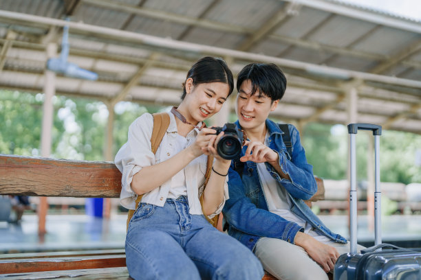 一对年轻夫妇在车站等火车时用相机捕捉记忆。旅行的概念。图片下载