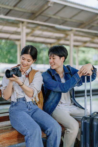 一对年轻夫妇在车站等火车时用相机捕捉记忆。旅行的概念。图片下载
