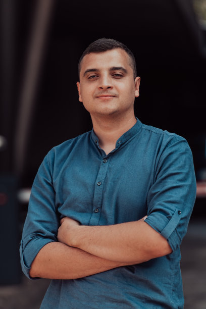 一个成功的年轻商人，穿着衬衫，双臂交叉，在户外摆姿势，脸上洋溢着自信。图片下载