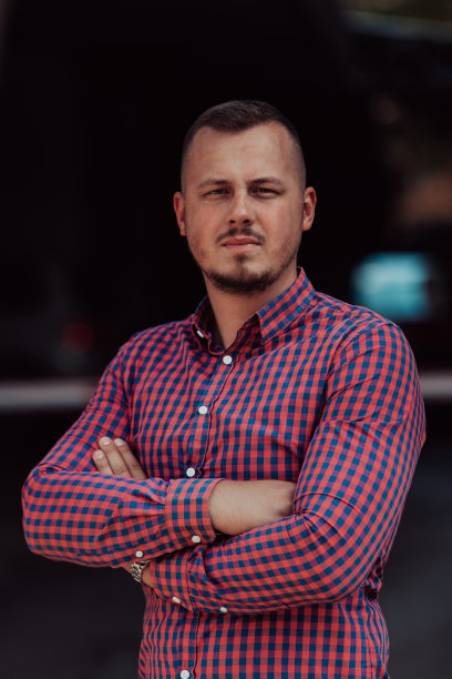 一个成功的年轻商人，穿着衬衫，双臂交叉，在户外摆姿势，脸上洋溢着自信。图片下载