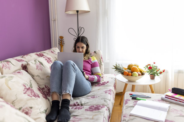 十几岁的自由职业者在家里的沙发上使用笔记本电脑图片下载