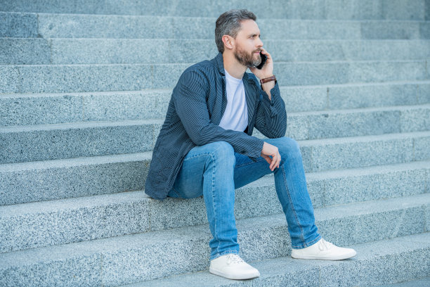 男人打电话聊天的照片。一个人坐在户外打电话。有电话的男人图片下载