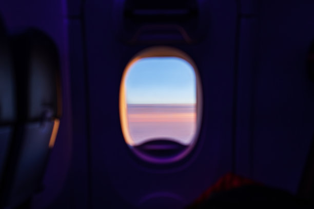 旅行主题是飞机的舷窗，看着外面柔和的云朵和阳光图片下载