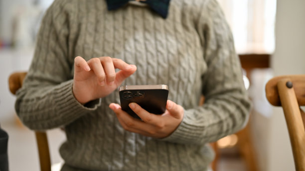 一位女性坐在咖啡店里使用智能手机的特写照片。图片下载