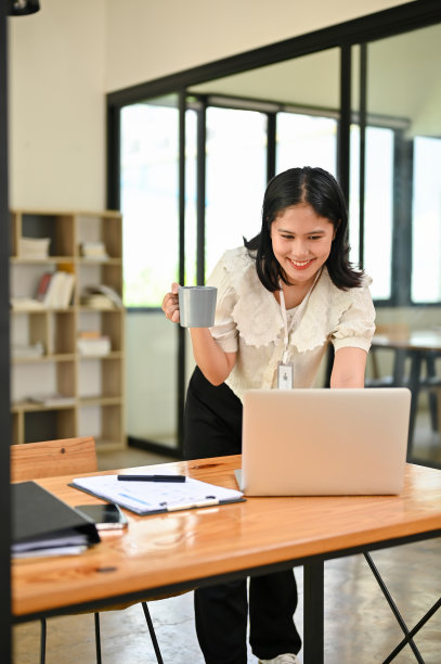 一位女商人趴在桌上的笔记本电脑前，用笔记本电脑处理她的业务任务。图片下载