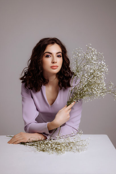 一个黑发女孩手里拿着一束吉普赛人花。图片下载