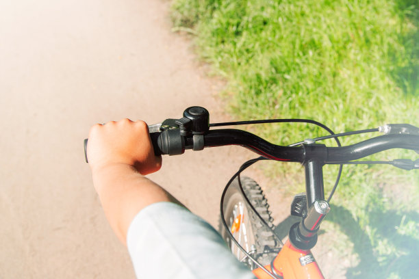 男孩的手放在自行车的把手上。从上面看。一个温暖的夏日。图片下载