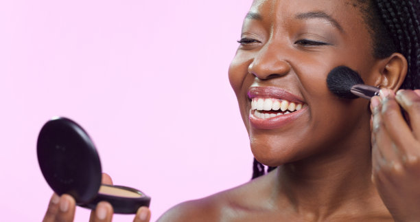 快乐，化妆和一个黑人妇女的脸红脸孤立在粉红色的背景在一个工作室。微笑，美丽和一个非洲模特使用面部化妆品的快乐，自信和脸颊颜色图片下载