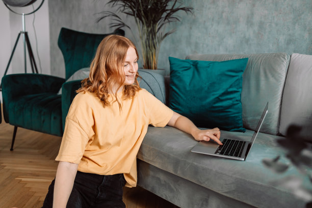 年轻漂亮的女人坐在豪华公寓的地板上拿着笔记本电脑图片下载