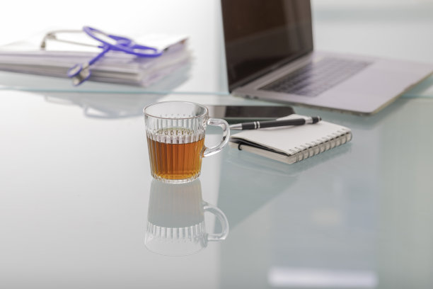 医生的玻璃桌上放着一台笔记本电脑和一个听诊器。图片下载