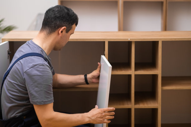 定制家具安装过程中，穿着工作服的木匠检查木柜的连接门图片下载