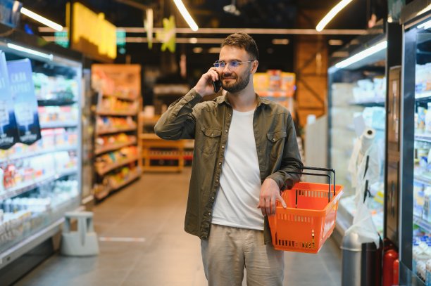 帅哥在超市购物，面带微笑，用着手机。图片下载