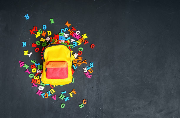 一个小小的充满活力的背包放在一堆五颜六色的字母上图片下载