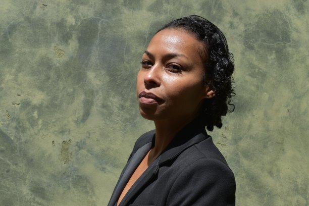 一个骄傲的年轻有色女商人的肖像，穿着黑色运动夹克，绿色的grunge背景。图片下载